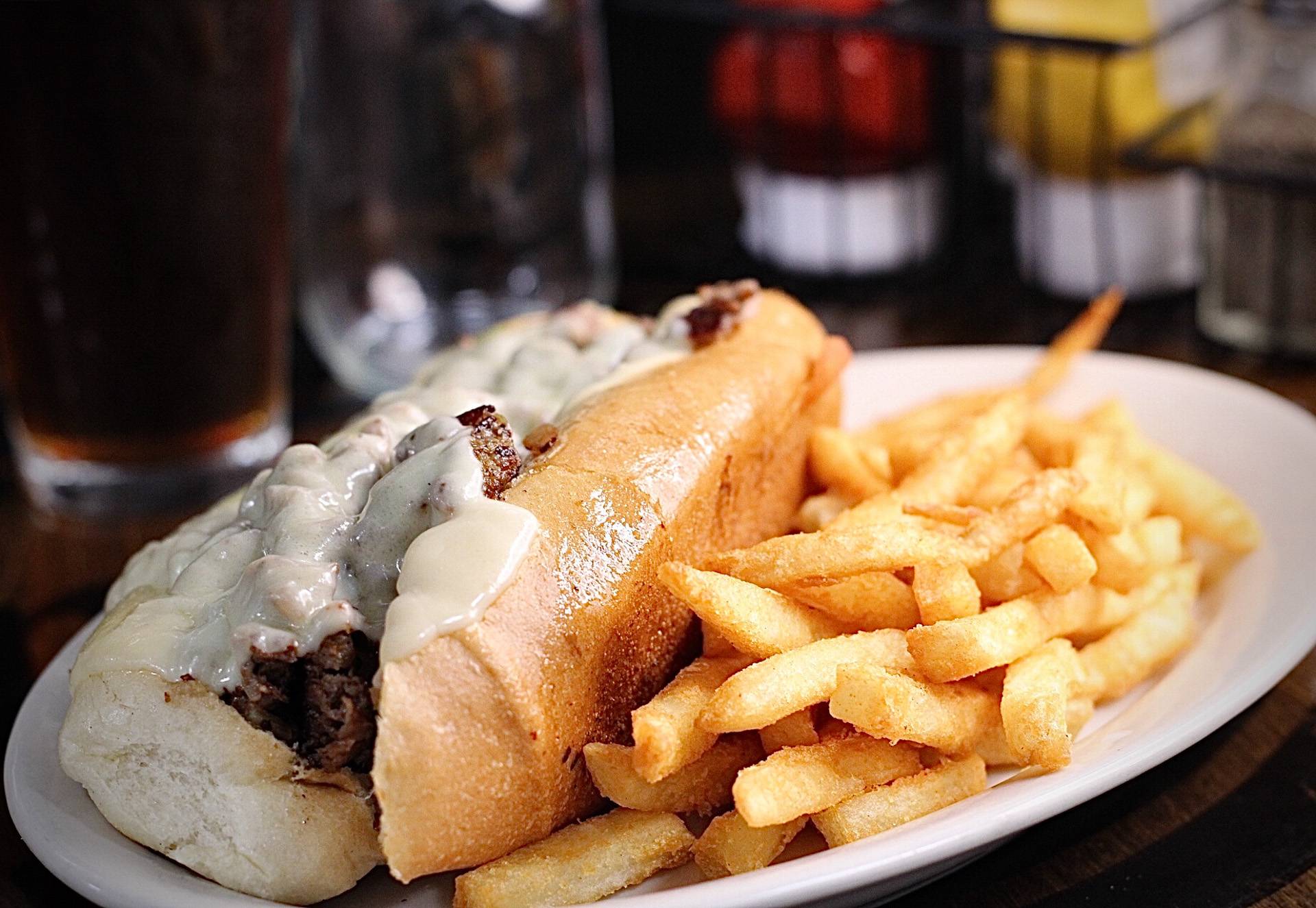 A close-up of the Philly Cheese Delight from Brooks Burgers, featuring tender beef, grilled onions, peppers, and melted provolone cheese in a freshly baked bun.