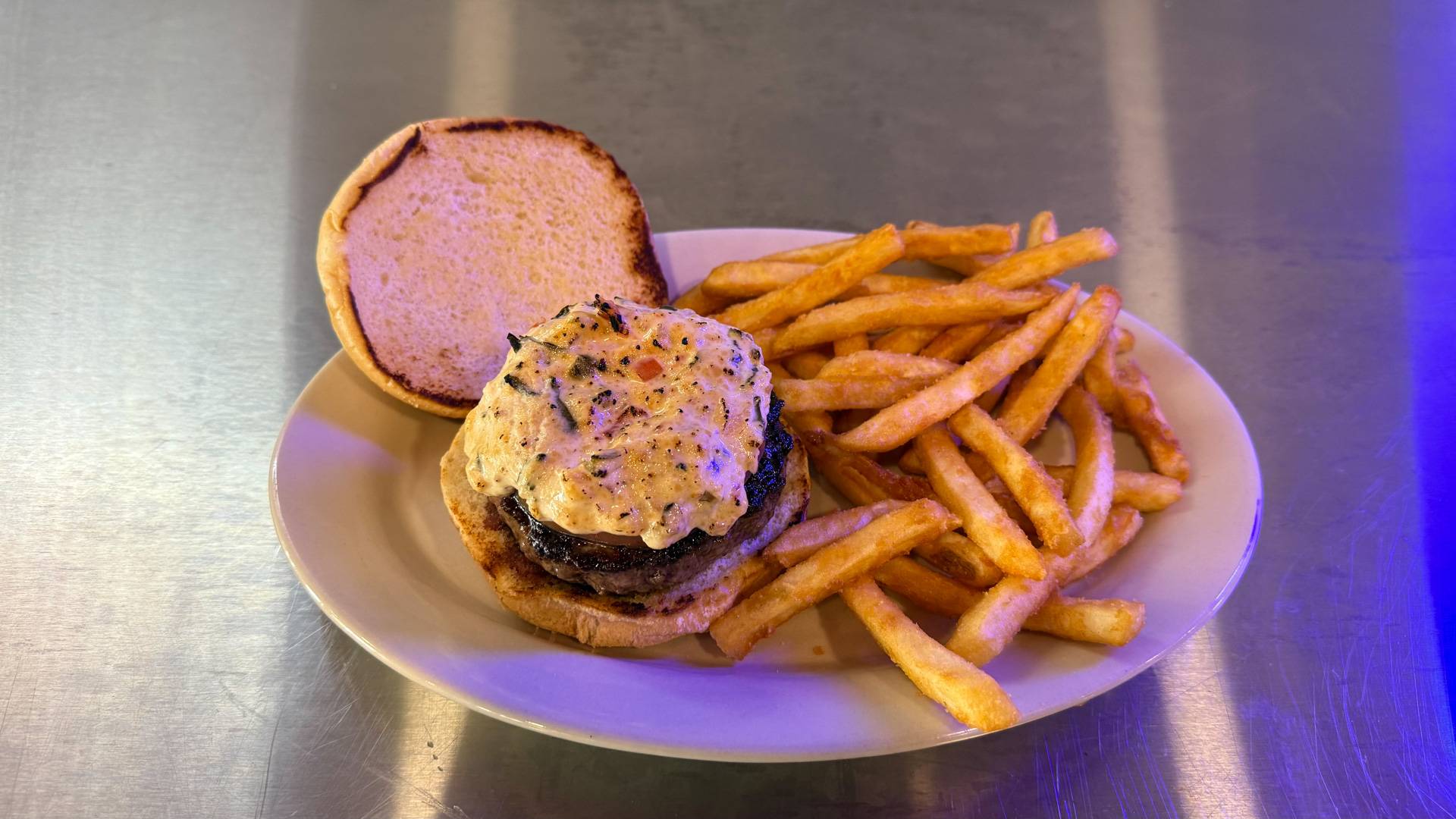 A gourmet burger from Brooks Burgers featuring a juicy beef patty topped with Asiago cheese and roasted garlic, presented on a soft, buttery bun.
