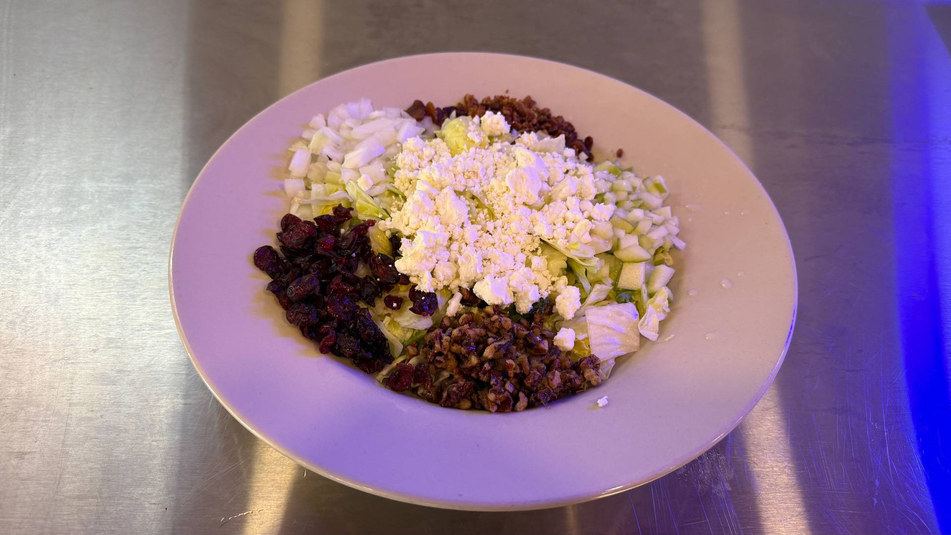 A vibrant, colorful salad showcasing Brooks Burgers' Harvest Chicken Salad with mixed greens, seasonal fruits, nuts, and cheeses adorned with a tangy vinaigrette.