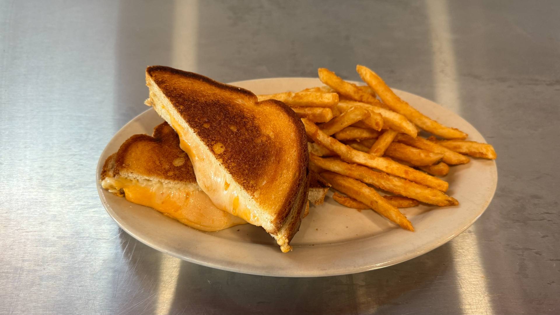 A savory gourmet burger with a melted cheese filled patty, served at Brooks Burgers in Naples, Florida, presented on a rustic wooden board with a side of crispy fries.