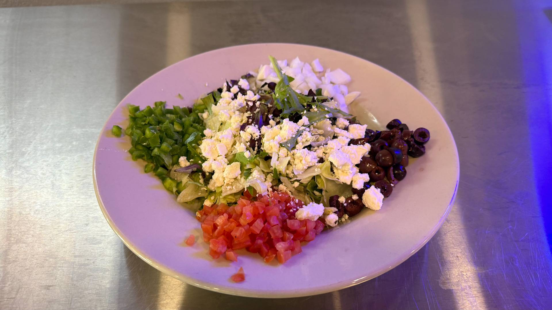Featured image of a vibrant Greek salad next to a juicy cheeseburger at Brooks Burgers, showcasing fresh ingredients like lettuce, tomatoes, cucumbers, and feta cheese.