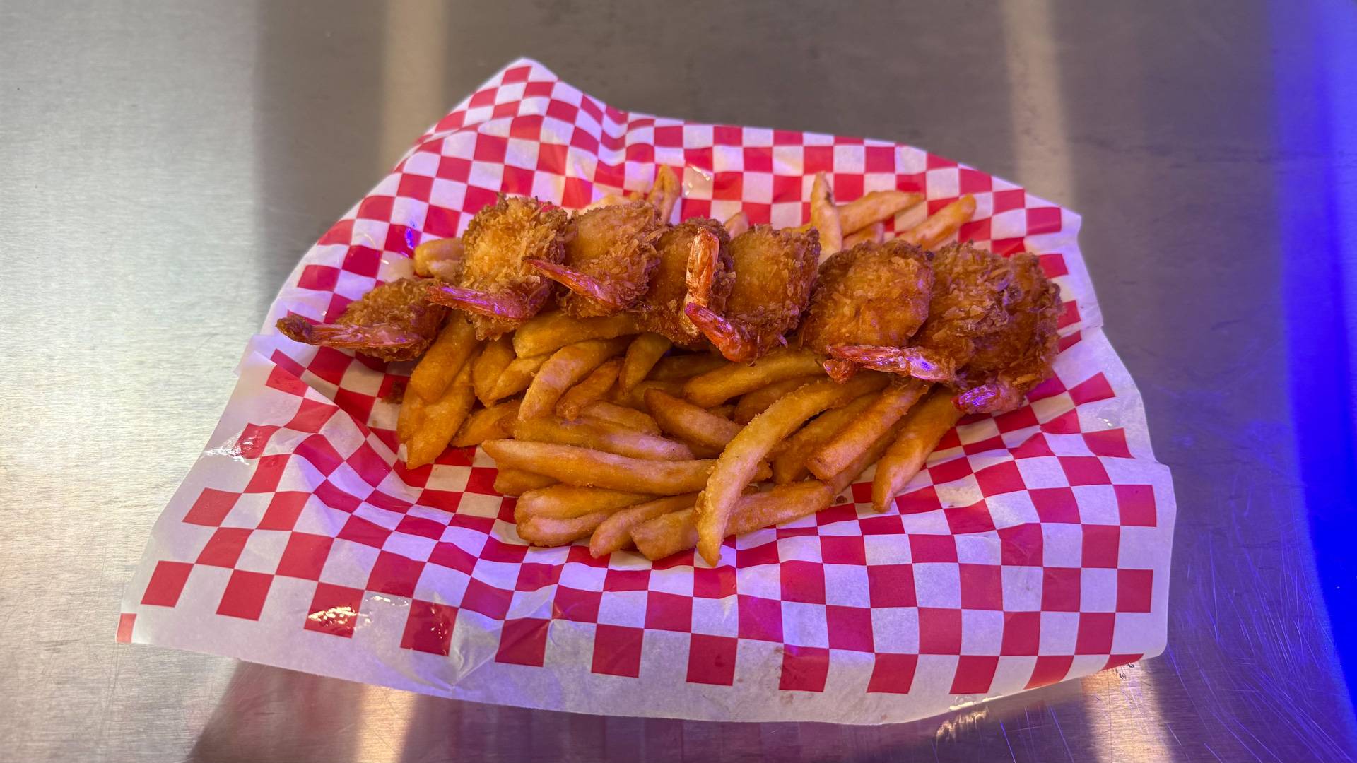 A mouth-watering Coconut Shrimp Basket with golden-brown shrimp coated in coconut batter, served with a zesty dipping sauce, highlighting the tropical and savory flavors available at Brooks Burgers in Naples.