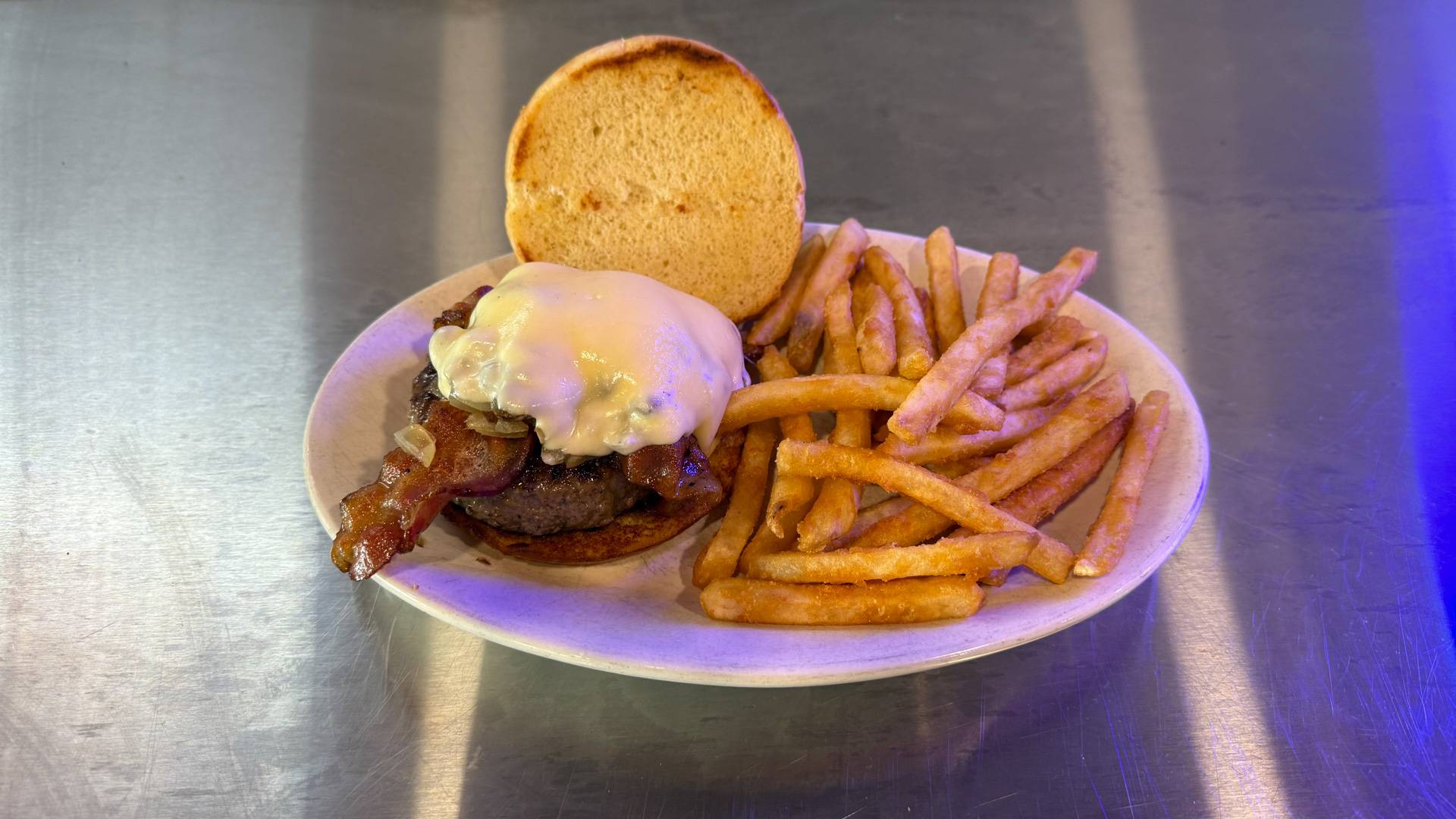 A tempting, freshly-made burger overflowing with toppings, served with a side of golden crispy fries on a wooden table, representing the delicious offerings at Brooks Burgers in Naples, Florida.