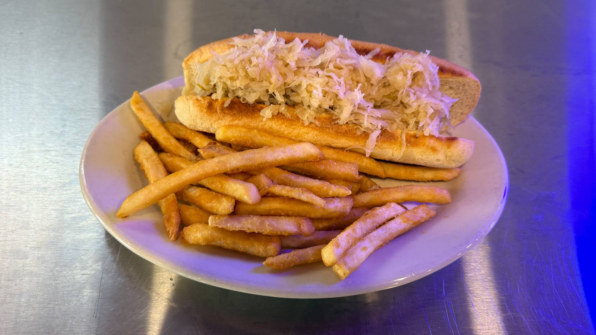 A Kraut Hot Dog Delight from Brooks Burgers in Naples, featuring a premium hot dog topped with sauerkraut, served in a toasted bun, on a rustic wooden table.