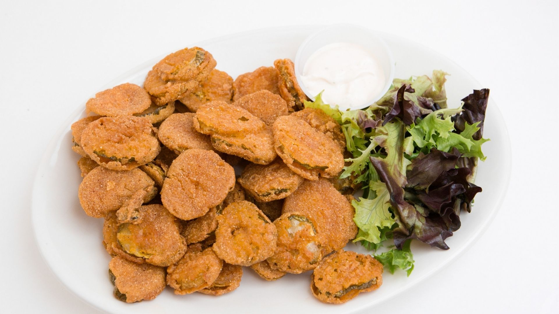 Plate of fried pickles with a crispy, golden-brown coating, garnished with a dip, at Brooks Burgers in Naples.